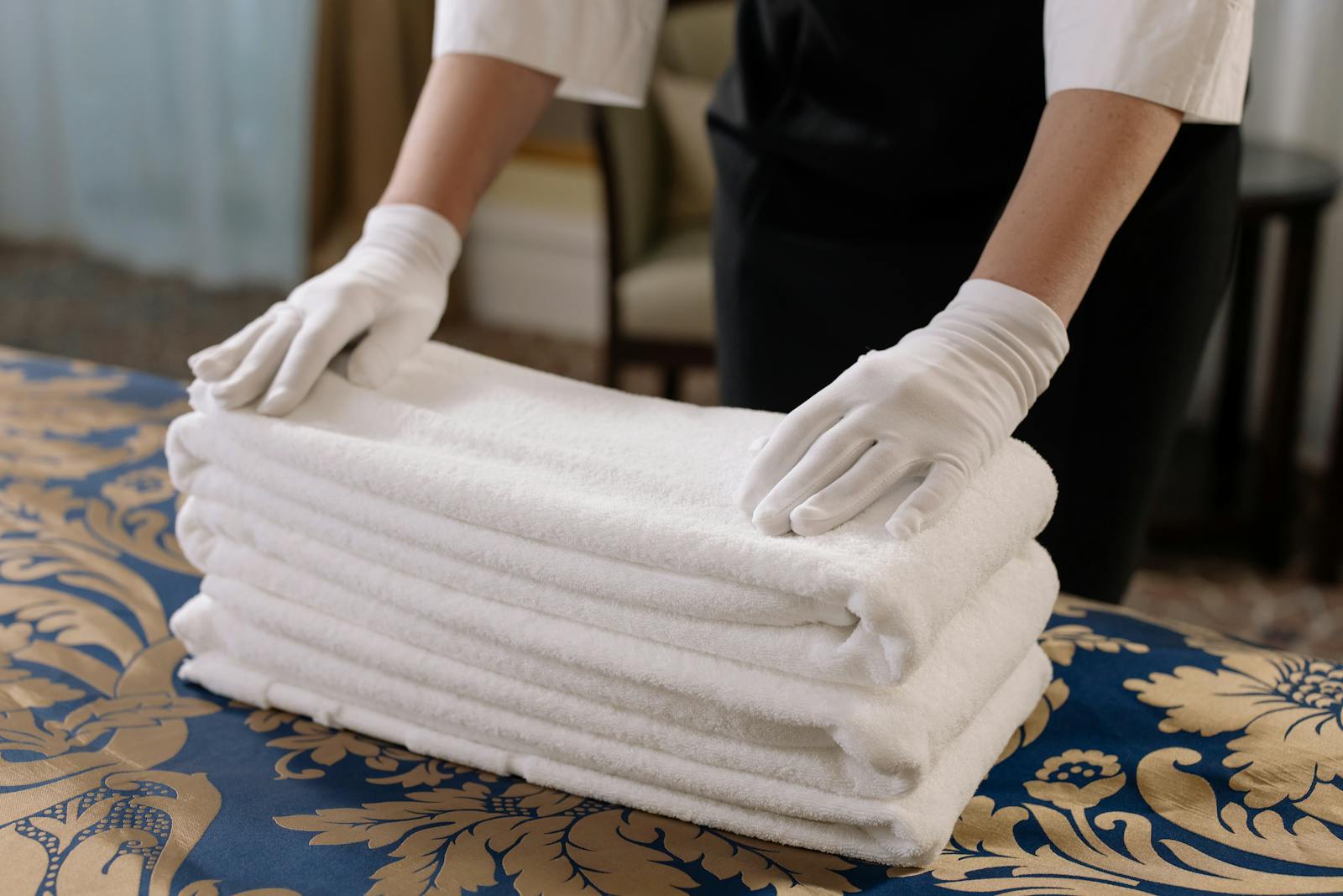 Person Holding a Stack of White Towels